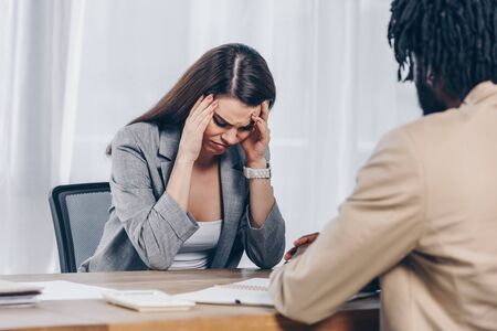 Selective focus of african american recruiter with worried and upset employee at job interview in officeの写真素材
