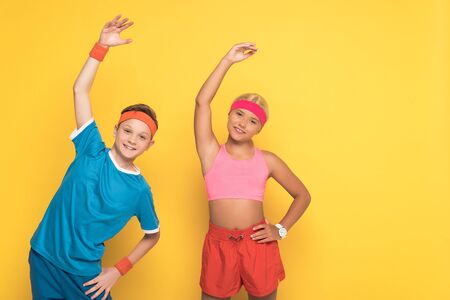 smiling kids in sportswear working out and looking at camera on yellow backgroundの写真素材