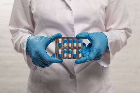 Cropped view of doctor holding blister with pills on white background