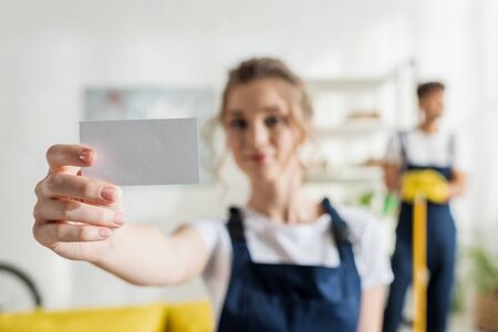 selective focus of beautiful cleaner holding blank card
