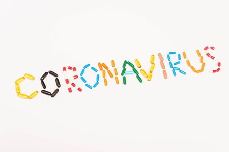 Top view of coronavirus lettering from colorful pills isolated on whiteの写真素材