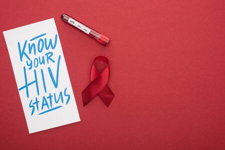 top view of card with know your HIV status lettering and awareness ribbon with blood sample on red...