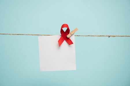 Empty card with aids awareness red ribbon on rope with pin isolated on blue