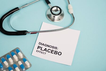 Card with placebo effect lettering, pills and stethoscope on blue backgroundの写真素材