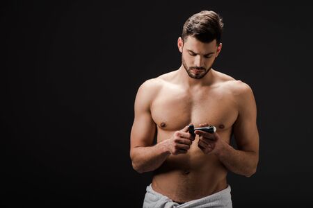 sexy brunette man looking at deodorant isolated on blackの写真素材