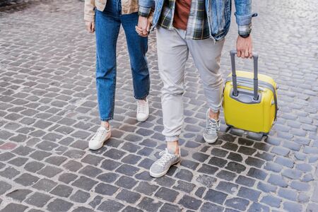 Cropped view of couple holding hands and traveling with suitcase togetherの写真素材