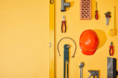flat lay with industrial tools, measuring tape and helmet, on yellow backgroundの写真素材