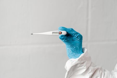 cropped view of person in latex glove holding thermometer, coronavirus conceptの写真素材