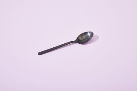 metal shiny black spoon on violet backgroundの写真素材