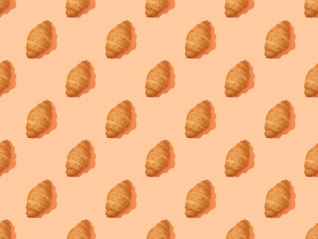 top view of fresh croissants on orange, seamless background patternの写真素材