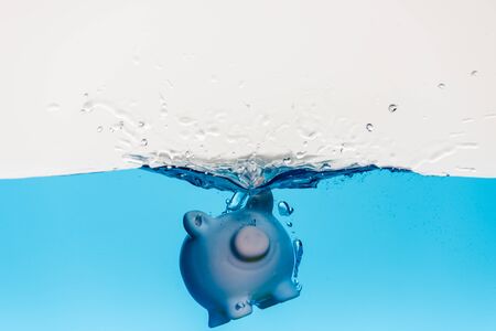piggy bank going under blue water with splash isolated on white, coronavirus crisis conceptの写真素材