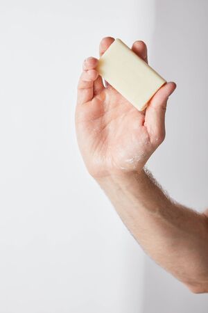 partial view of man holding soap in hand on grey background backgroundの写真素材