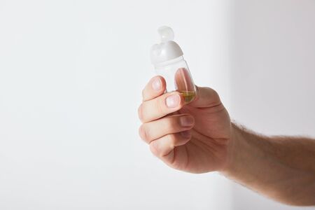 cropped view of man holding hand sanitizer on grey background