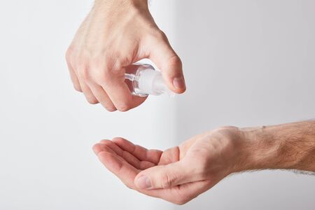 cropped view of adult man using hand sanitizer on white background
