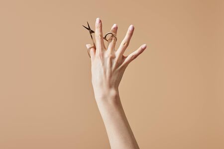Cropped view of woman holding nail scissors isolated on beigeの写真素材