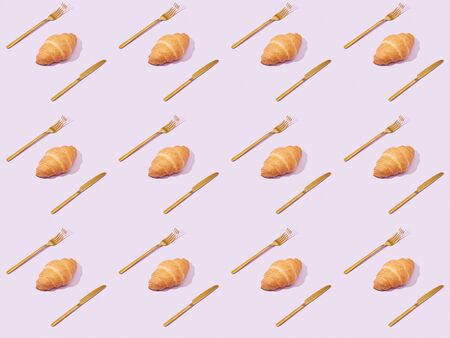 golden forks and knives with croissants isolated on violet, seamless background patternの写真素材