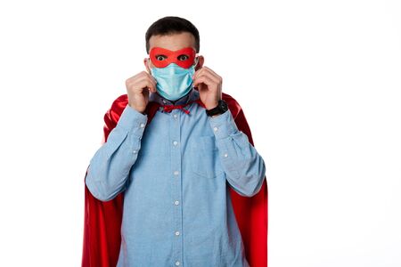 man in superhero costume touching medical mask isolated on whiteの写真素材