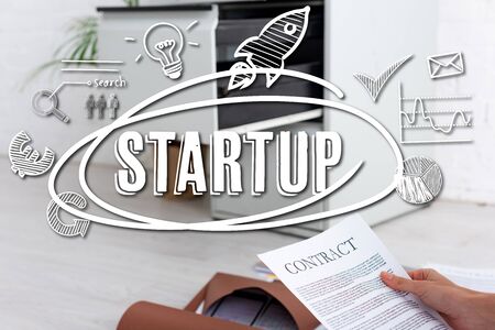 Cropped view of businesswoman holding contract near paper folders on floor, startup illustrationの写真素材