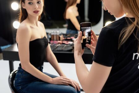 selective focus of makeup artist taking photo of young modelの写真素材