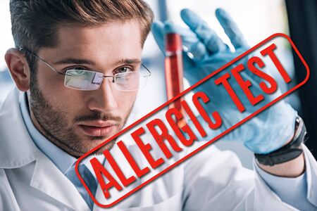 selective focus of bearded allergist in glasses holding test tube with red liquid with allergic test illustrationの写真素材