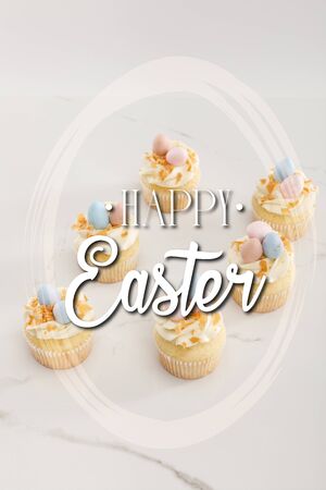 Delicious easter cupcakes with painted quail eggs on top on white background with happy Easter illustrationの写真素材