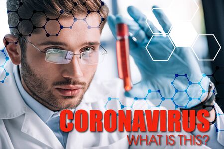 selective focus of bearded immunologist in glasses holding test tube with red liquid and coronavirus illustrationの写真素材