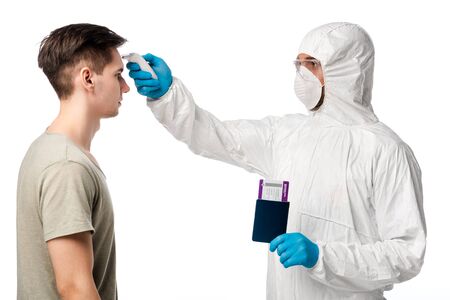 doctor in personal protective equipment holding pyrometer and passport with boarding pass near man...