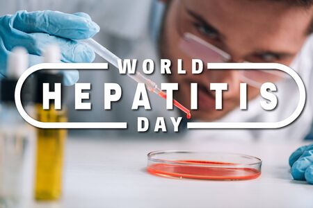 selective focus of scientist holding pipette with red liquid in lab with world hepatitis day illustrationの写真素材
