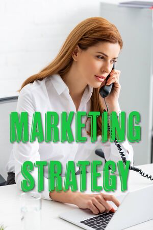 Successful businesswoman using laptop and talking on phone at office table, marketing strategy illustrationの写真素材