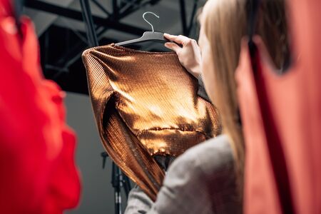 selective focus of stylist holding trendy blouse on hangerの写真素材
