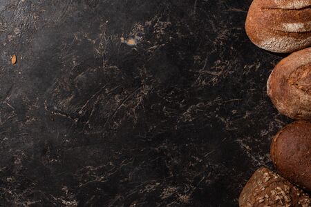 top view of fresh baked whole grain bread on stone black surface