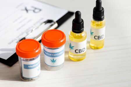 selective focus of bottles with medical cannabis and cbd lettering near clipboard