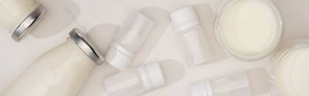 Top view of bottles and glasses of homemade yogurt near containers with starter cultures on white, panoramic shotの写真素材