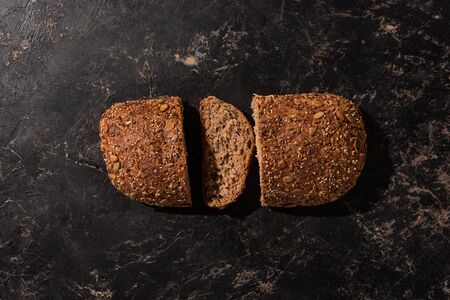 top view of cut whole grain bread on stone black surfaceの写真素材