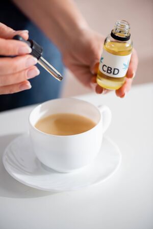 cropped view of mature woman adding cbd in cup of tea on tableの写真素材