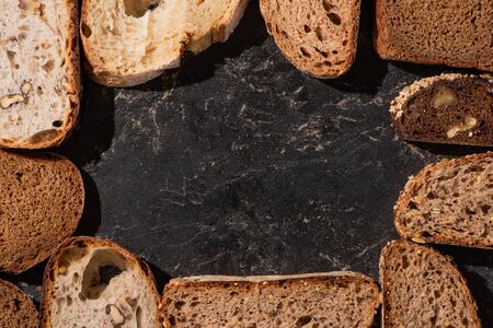 top view of fresh baked bread slices on stone black surfaceの写真素材