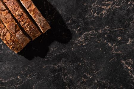 top view of fresh bread slices on stone black surface