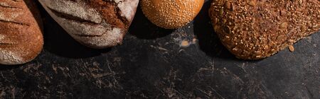 top view of fresh baked bread on stone black surface, panoramic shot