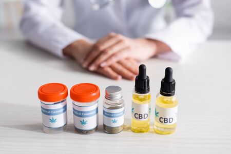 selective focus of bottles with cbd and medical cannabis lettering near doctorの写真素材