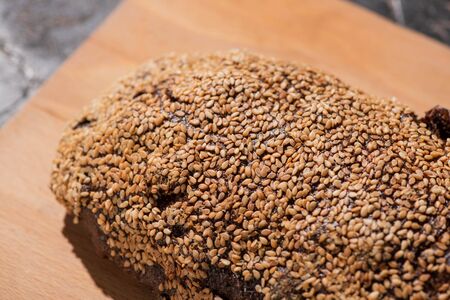 fresh baked black bread with sesame on cutting boardの写真素材
