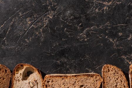 top view of fresh baked bread slices on stone black surfaceの写真素材