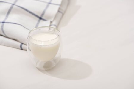 High angle view of glass of homemade yogurt near plaid fabric on white backgroundの写真素材