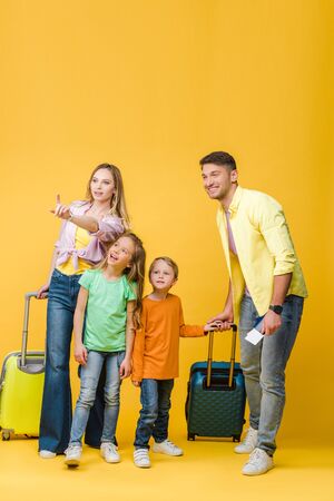 happy family of travelers with luggage, passports and tickets pointing on yellowの写真素材