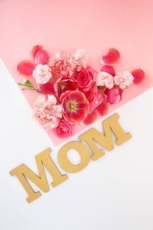 top view of flowers and mom lettering on pink and white backgroundの写真素材