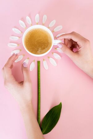 top view of woman touching cup of coffee near white petals on pink, mothers day conceptの写真素材