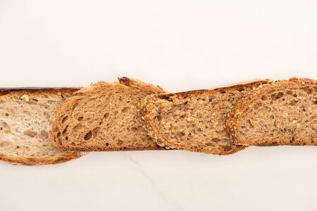top view of whole grain bread slices in line on white backgroundの写真素材