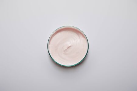 Top view of laboratory glassware with pink cosmetic cream on grey background