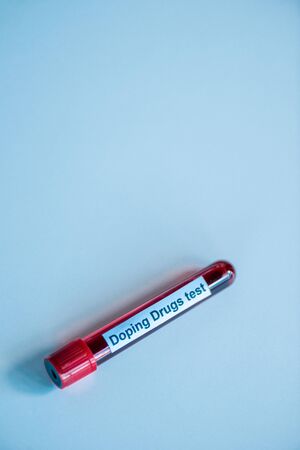 top view of glass test tube with blood sample and doping drugs test lettering on blue