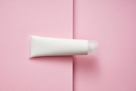 Top view of plastic tube with white cosmetic cream on pink backgroundの写真素材