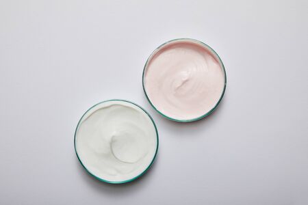 Top view of laboratory glassware with white and pink cosmetic cream on grey backgroundの写真素材